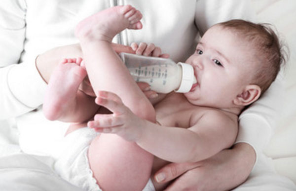 Грудничок в подгузнике пьет из бутылочки